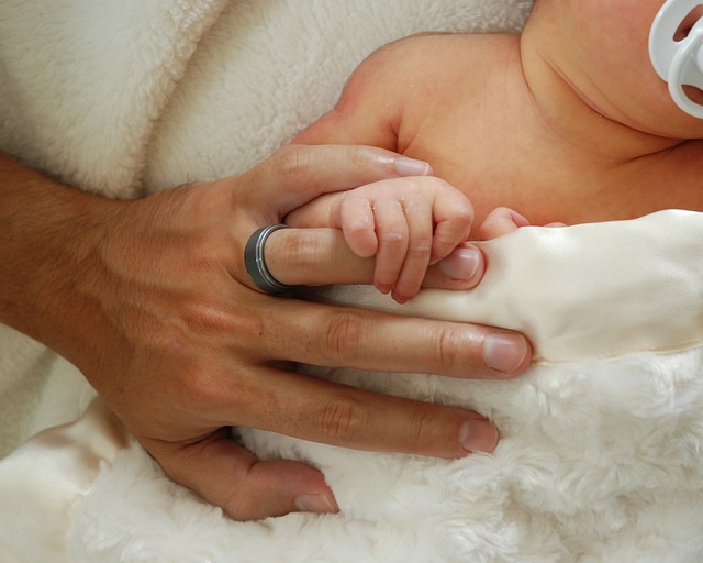 otec drží ruku malého kojence